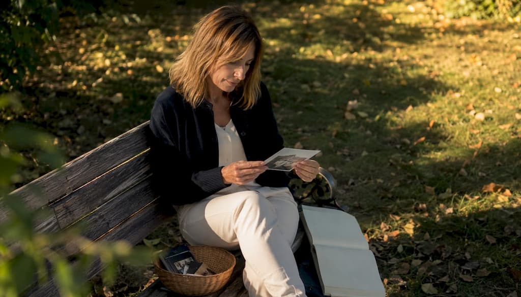 Une femme prend le temps d’observer attentivement une photo imprimée chez elle.