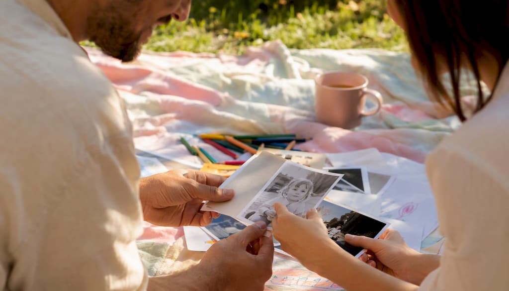 Des mains étalent des photos d’enfance sur la table, prenant le temps de les disposer avec soin.