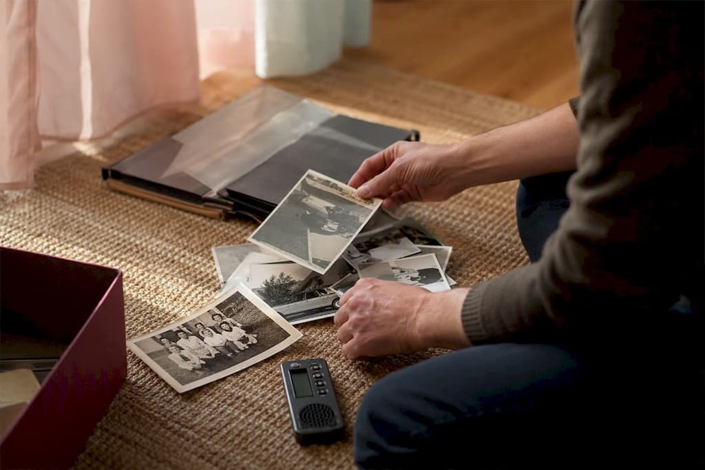 Des mains qui trient des photos à côté d’un dictaphone