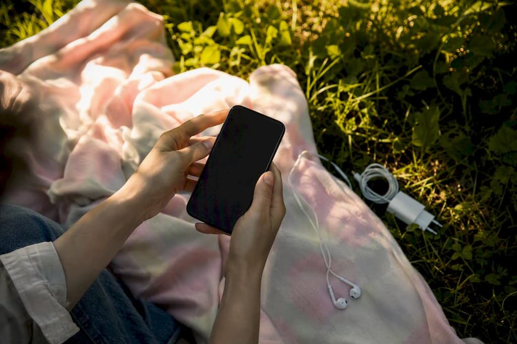 Mains tenant un smartphone en extérieur